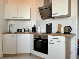 a kitchen with white cabinets and a black oven at H&W Apartments I in Wolmirstedt