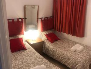 a bedroom with two beds with red curtains and a mirror at Villa Corazon in Torrevieja +10 photos