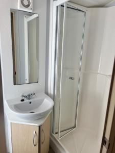 a white bathroom with a sink and a shower at Red Deer Village Holiday Park - 3 Bedroom, Self-Catering Holiday Home in Steps +39 photos
