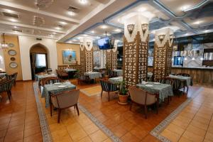 a restaurant with tables and chairs and a tv at Kazzhol Hotel Astana in Astana