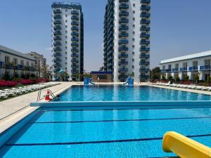 a large swimming pool with two tall buildings at Deniz Manzaralı Rezidans Daire in Saint Yeorgios