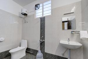 a white bathroom with a toilet and a sink at Livora Residency in Chennai