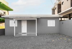 a white building with a door in a parking lot at Edícula Cambará in Cambará