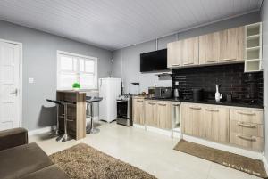 a kitchen with wooden cabinets and a black brick wall at Edícula Cambará in Cambará