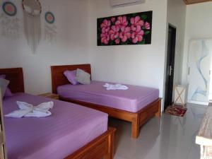 two beds in a room with purple sheets at Compass Homestay in Huu