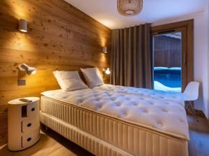 una camera da letto con un letto grande con una parete in legno di Chalet Méribel 6 pers., jacuzzi, ski-in/ski-out - FR-1-355-211 a Les Allues