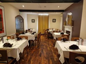 a restaurant with white tables and chairs and a fireplace at Room near East Midland Airport 6 in Kegworth