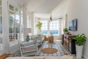 una sala de estar con paredes y ventanas blancas. en The Boulders House, en Ciudad del Cabo
