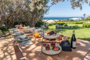una mesa con platos de comida y una botella de vino en The Boulders House, en Ciudad del Cabo