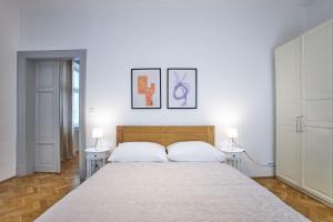 a white bedroom with a large bed with two lamps at Wenceslas Square Residence in Prague