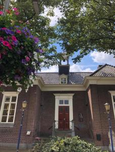 a red brick house with a red door and flowers at Boetiekhotel Ons Oude Raadhuis in Hooge Zwaluwe