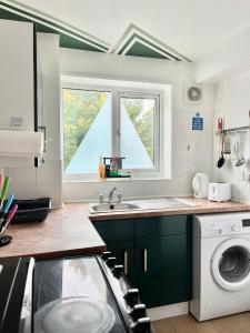 a kitchen with a sink and a washing machine at The Express Apartment in Goodmayes