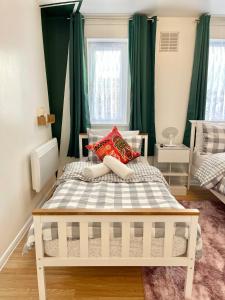 a bedroom with a white bed with green curtains at The Express Apartment in Goodmayes