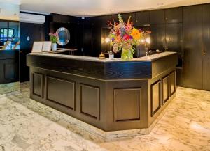 een lobby met een balie met een vaas met bloemen bij rugs HOTEL Köln in Keulen