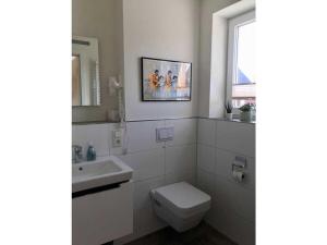 a bathroom with a toilet and a sink and a window at Holiday home Ankerherz in Butjadingen +9 photos