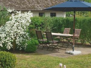 a table and chairs under an umbrella next to a bush at Captain House South Cats 8 in Wieck