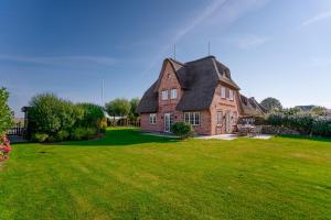 una grande casa di mattoni con un tetto nero su un prato verde di LITZKOW 16204 ad Archsum