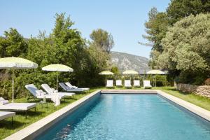 a swimming pool with lounge chairs and umbrellas next to at La Bastide du Mourre - Fontenille Collection in Oppède