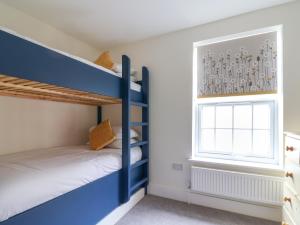 a bedroom with bunk beds and a window at Belfry Cottage in Colyton