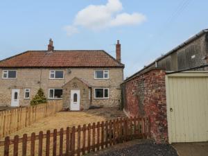 a brick house with a fence and a gate at Bellmanear Farm Cottage in Malton