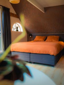 a bedroom with a bed with orange sheets and a window at De Smederij in Bolsward