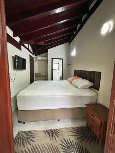 a bedroom with a large bed and a tv at Apartamento com varanda em frente a Praia de Maresias in São Sebastião