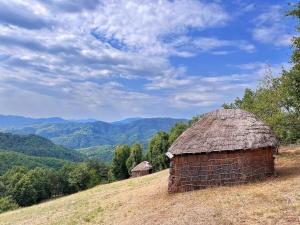 un antiguo granero en una colina con montañas en el fondo en ВИЛА ЯНА Villa Yana, en Presoka