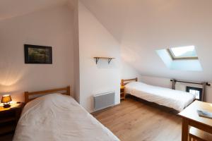 a attic bedroom with two beds and a window at Gîte Gîte de France 6/10 personnes à La Ferme Lionnet in Albaret-le-Comtal
