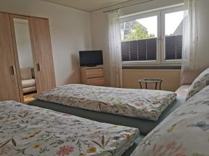 a bedroom with two beds and a tv and a window at Strandhaus Deichvoigt in Cuxhaven