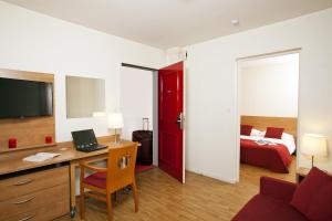 レンヌにあるセジュール＆アフェール レンヌ ヴィラ カミラのデスクとベッドが備わるホテルルームです。