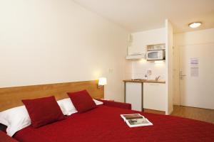 ein Hotelzimmer mit einem roten Bett mit einer roten Decke in der Unterkunft Séjours & Affaires Rennes Villa Camilla in Rennes