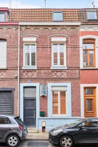 two cars parked in front of a brick building at Maison 4 chambres et jacuzzi pour 8 personnes in Roubaix