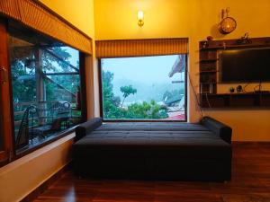 a living room with a large window and a couch at Woody Trails - Astronomy, Graphology, Family, Kainchi Dham in Bhowāli