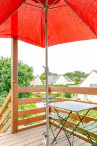 a red umbrella and a chair on a deck at A 600 m de la plage avec jardinet privatif in Saint-Pierre-Quiberon