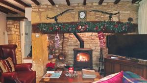 a living room with a stone fireplace with a tv at Graziers Cottage - character Cotswold cottage with inglenook, parking and pub nearby in Cheltenham