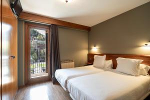 a hotel room with two beds and a window at Aparthotel AnyosPark Mountain & Wellness Resort in Anyós