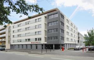 - un grand bâtiment blanc dans une rue de la ville dans l'établissement Séjours & Affaires Rennes Villa Camilla, à Rennes