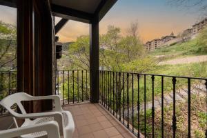a room with a balcony with two chairs and a view at Aparthotel AnyosPark Mountain & Wellness Resort in Anyós