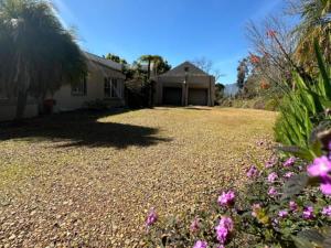 a house with a gravel driveway with flowers at Madajo in Stellenbosch