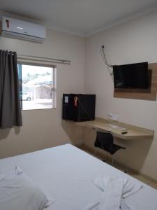 une chambre avec un lit et un bureau avec un ordinateur dans l'établissement Palmares Hotel, à Guaíra