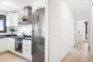a kitchen with white cabinets and a stainless steel refrigerator at MEDANO4YOU Westside Penthouse in El Médano +27 photos