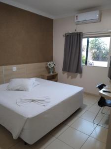 une chambre avec un lit blanc et une fenêtre dans l'établissement Palmares Hotel, à Guaíra