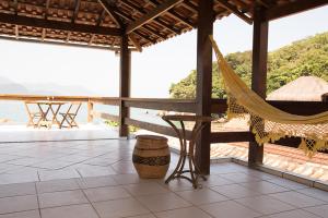 a porch with a hammock and a view of the ocean at Casa 1 - Você a Varanda e o Mar na Praia dos Ranchos-Trindade Hospeda in Trindade