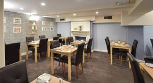 a dining room with tables and chairs and a fireplace at Marton Guest House in St. Peter Port