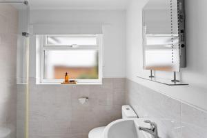 Un baño con inodoro, lavabo y ventana. en 15 Churchfields - Bungalow with Estuary Views and Parking, en Dartmouth