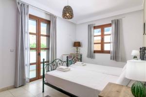 a white bedroom with a bed and windows at Lindos Sapphire in Lindos +14 photos