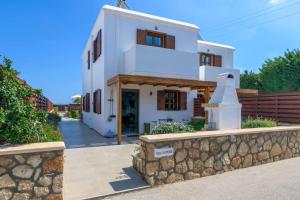 a white house with a stone wall in front of it at Lindos Sapphire in Líndos