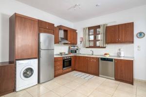 a kitchen with wooden cabinets and a washer and dryer at Lindos Sapphire in Lindos
