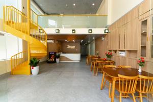a restaurant with wooden tables and chairs and a staircase at DRAGON HUE HOTEL in Hue