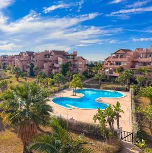 a swimming pool with palm trees and houses at Casa Golf Mar Menor in Los Martínez